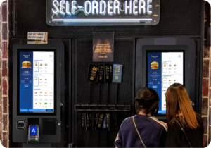 customers using self ordering kiosk in restaurant